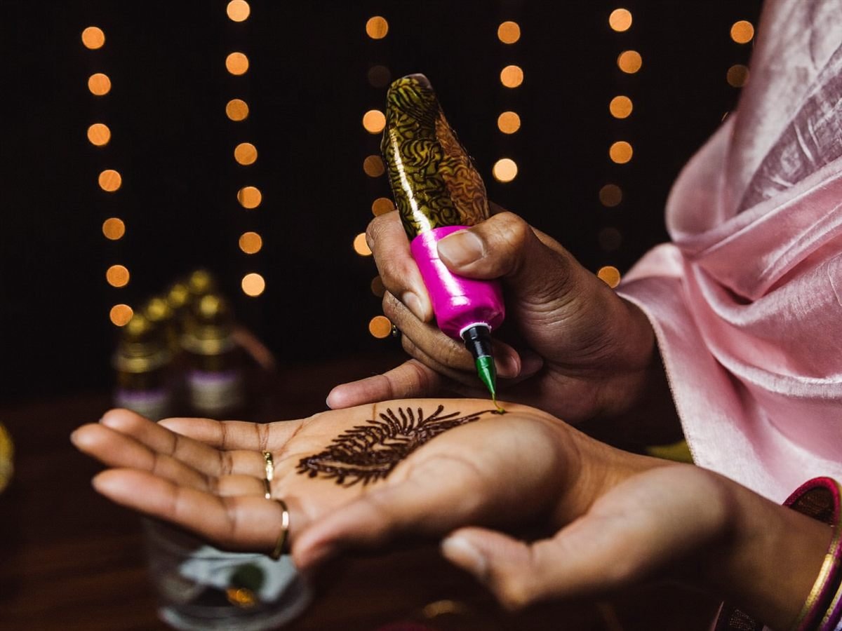 Mehndi being applied at a sangeet, warm lights in the background