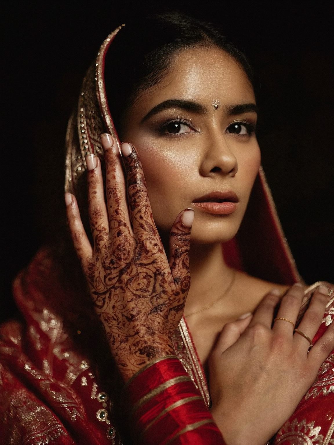 Bride with finished soft-glam makeup and dark bridal henna on her raised hand
